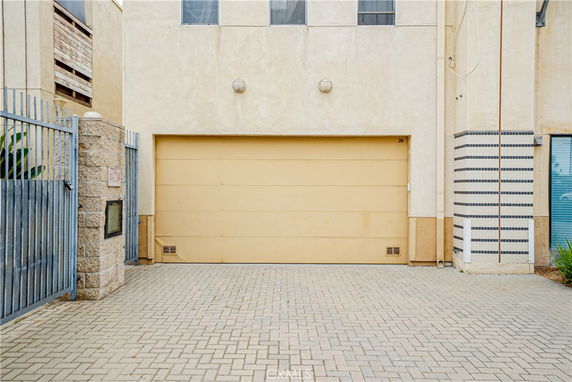 Front view of a building with a garage door and fenced entrance.