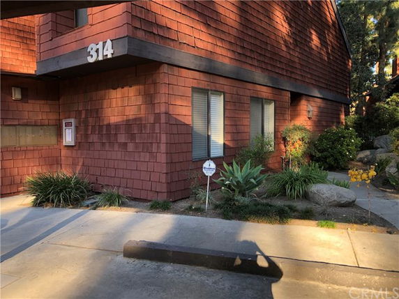 Front view of a building with wooden shingles and window shades.