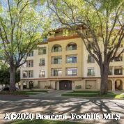 Front view of a multi-story building with arched windows and trees in front.