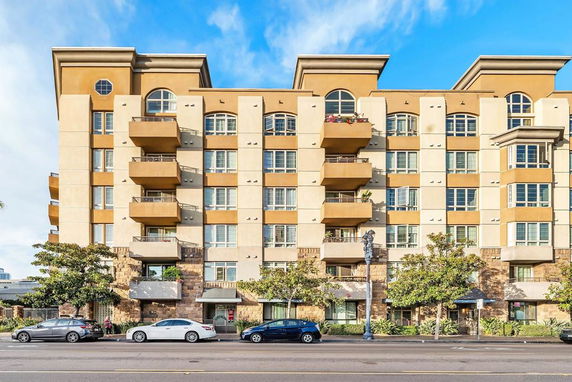 Front view of a multi-story residential building with balconies and large windows.