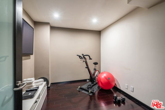 Room with exercise equipment including a stationary bike and a stability ball.