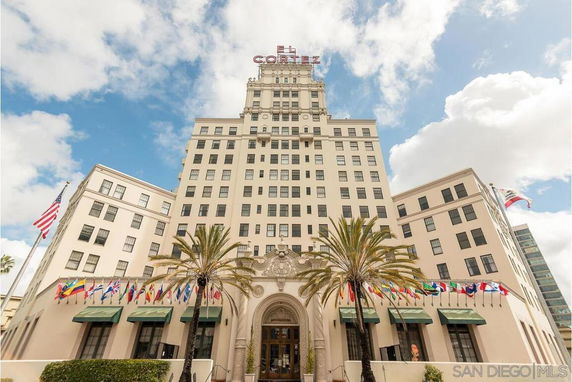 Front view of a multi-story building with decorative entrance and flags.