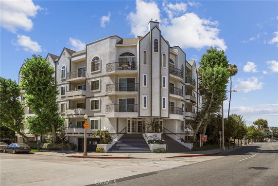 Front view of a multi-story residential building with balconies and decorative architectural elements.