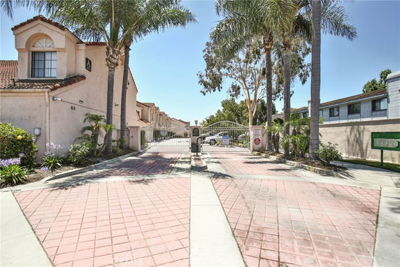 Front view of a gated residential complex with a pathway leading to the entrance.