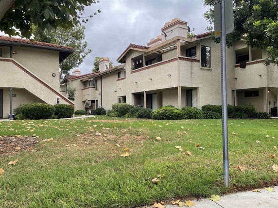 Front view of a multi-story residential building with beige walls and red tile roofs.