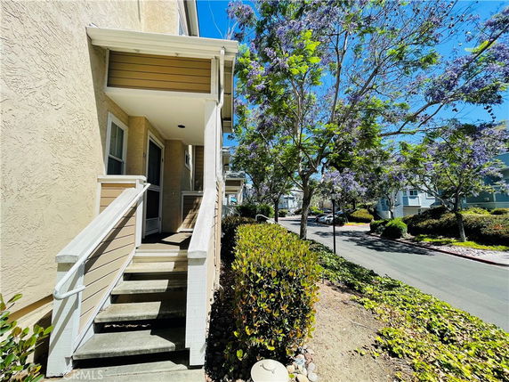 Front view of a two-story house with a small porch and staircase leading to the entrance.