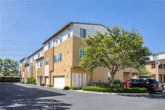 Front view of a multi-story residential building with garages and windows.