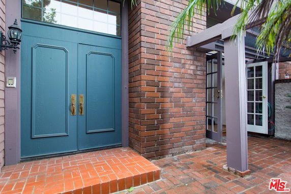 Front view of a house with a blue double door entrance and brick exterior.
