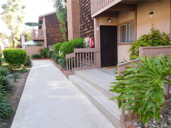 Front view of a residential building entrance with stairs and a walkway.