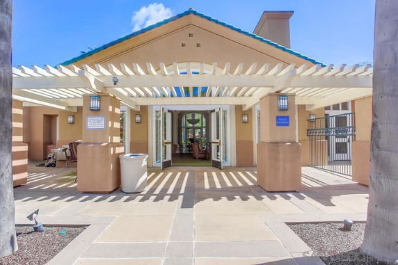 Front view of a building with a pergola entrance and seating area.