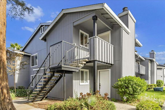 Front view of a two-story house with an external staircase leading to the upper floor.