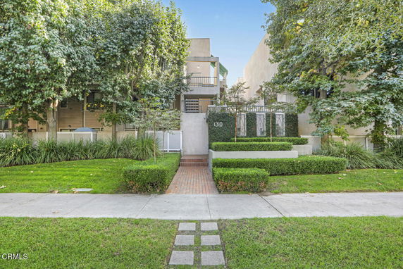 Front view of a multi-story residential building with a landscaped entrance.