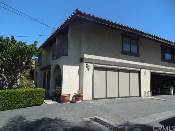 Front view of a two-story house with a garage on the ground level and a balcony.