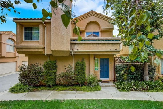 Front view of a two-story house with a blue front door and decorative greenery.