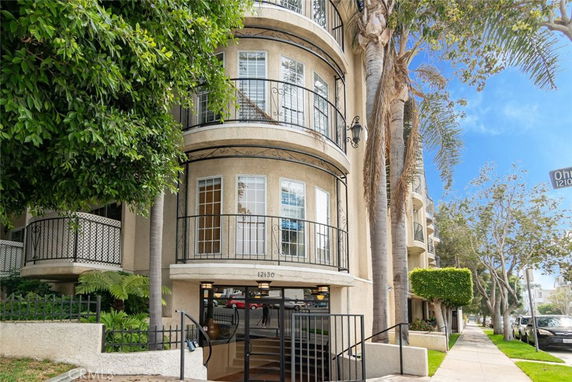 Front view of a multi-story building with balconies and arched windows.