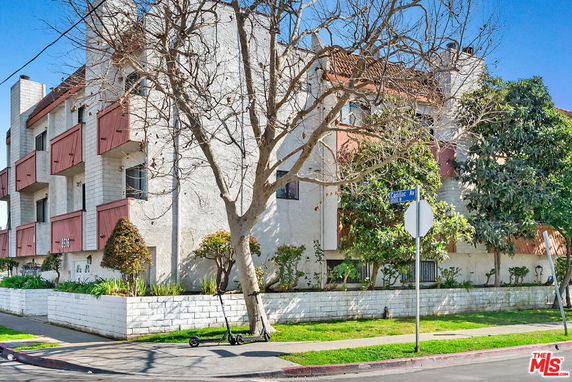 Front view of a multi-story apartment building with balconies and a white exterior.
