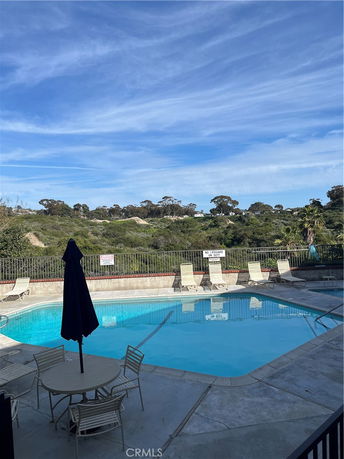 Outdoor swimming pool with lounge chairs and umbrella.