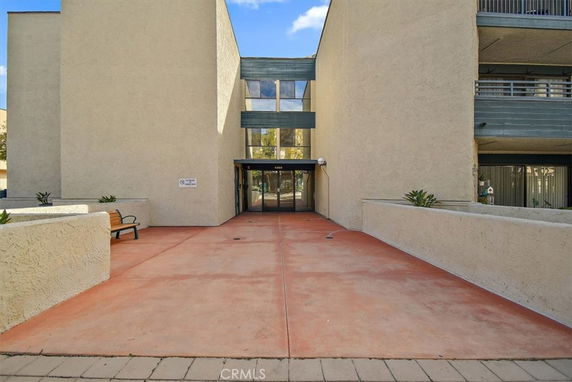 Front view of a multi-story building entrance with a flat facade and walkway.