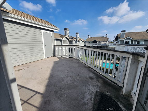 Rooftop area with railing and wooden storage structure, overlooking residential buildings.