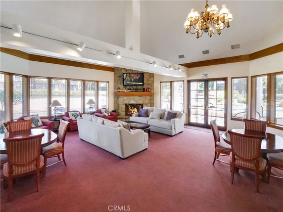 Room with seating areas, tables, and a fireplace, lit by a chandelier.