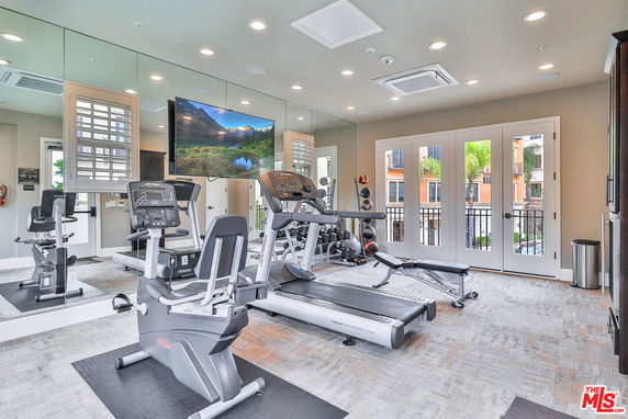 Indoor gym area with exercise equipment and large mirrors.