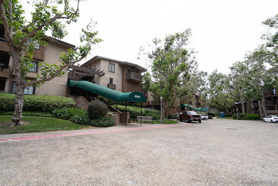 Front view of an apartment building with multiple levels and green awnings over the entrances.