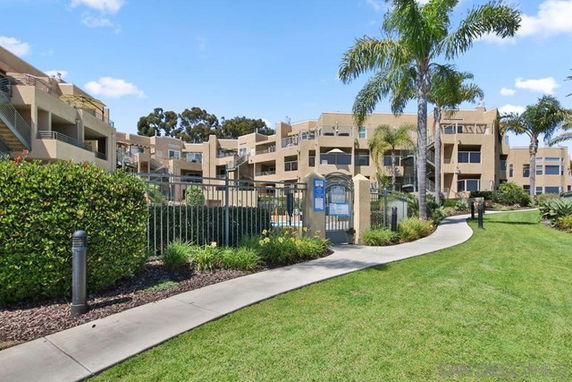 Front view of a multi-story residential building with balconies and palm trees.