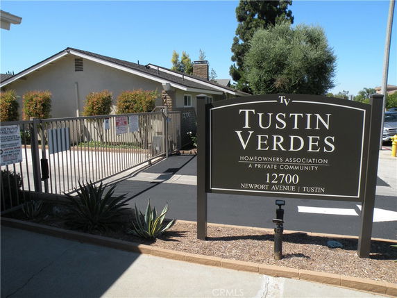 Front view of a residential building in a private community with signage for Tustin Verdes.