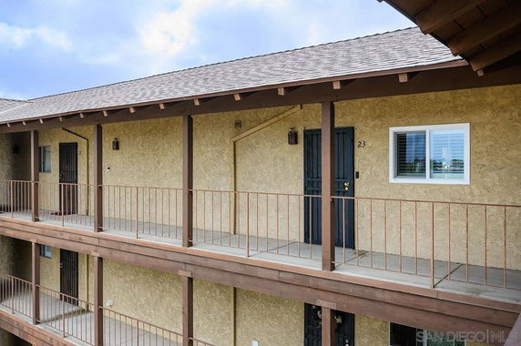 Exterior view of a multi-story building with balcony walkways and metal railings.
