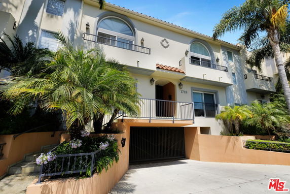 Front view of a multi-story residential building with balconies and a gated entrance.