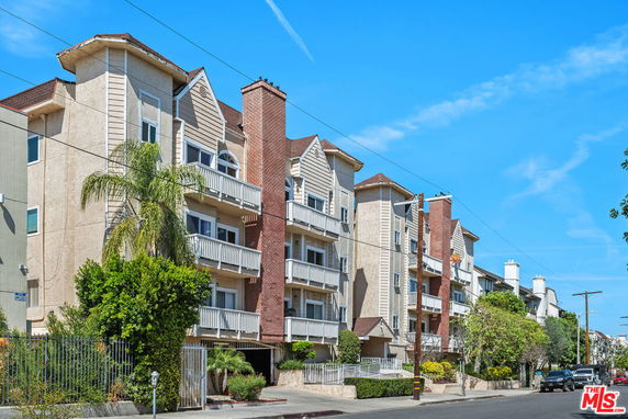 Front view of multi-story apartment building with balconies and brick accents.