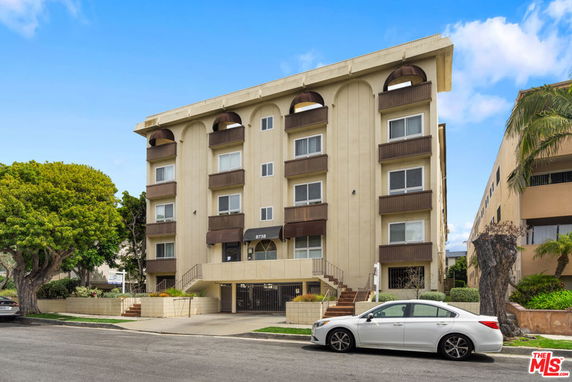 Front view of a multi-story residential building with balconies and a gated entrance.