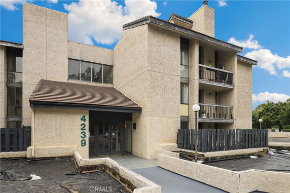 Front view of a multi-story building with balconies and a sloped roof.