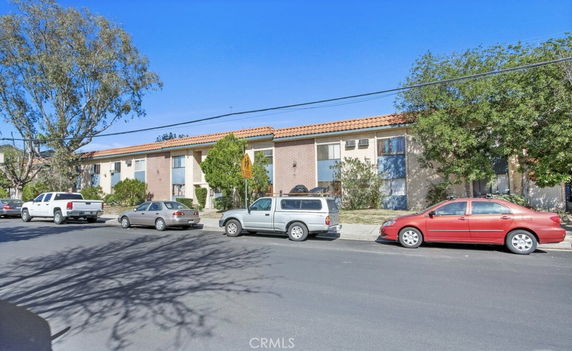 Front view of a two-story residential building with cars parked in front.