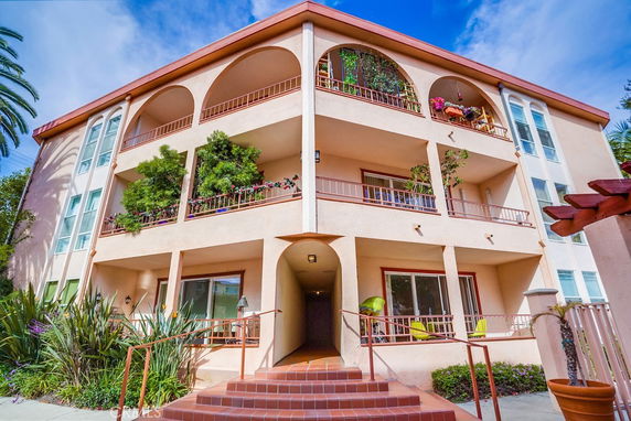 Front view of a three-story apartment building with arches and balconies.