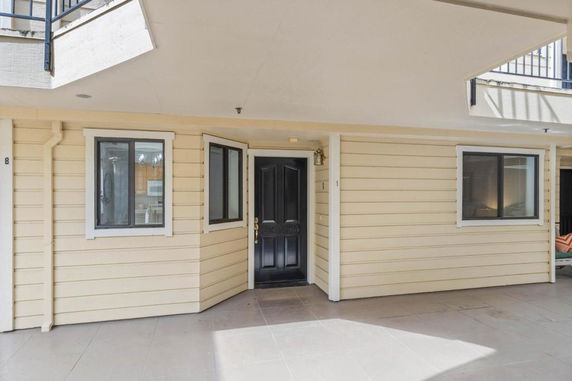 Front view of a building with beige siding and a black door.