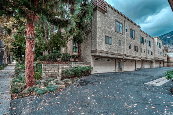 Front view of a multi-story apartment building with several garages on the ground level.