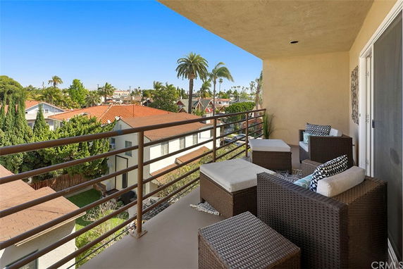 View from a balcony overlooking rooftops and palm trees.