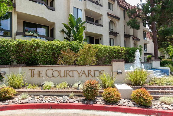 Front view of an apartment building with a fountain and signage reading 'The Courtyards'.