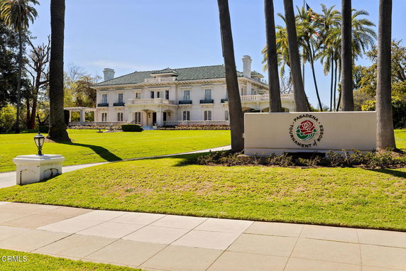 Front view of a large two-story house with a green roof and balconies.