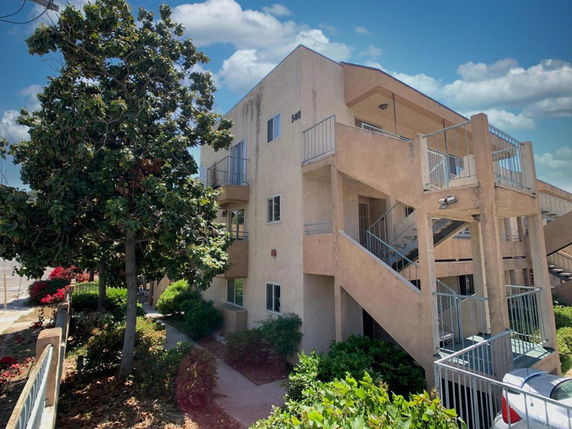 Front view of a multi-story building with external staircase.
