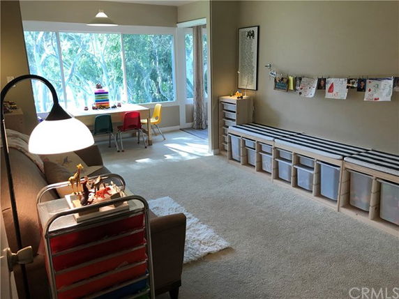Room with children's play area featuring colorful chairs, a small table, and storage bins.