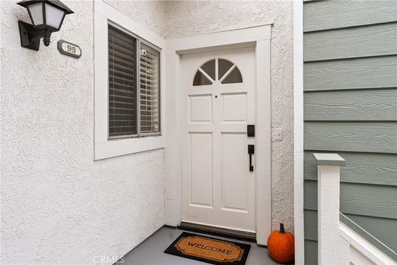 Front view of a house entrance with a white door and a welcome mat.
