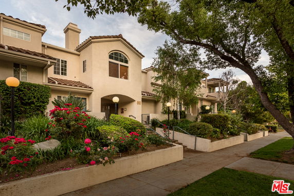 Front view of a two-story residential building with arched windows and landscaped entrance.