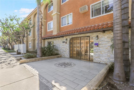 Front view of a multi-story building with decorative gate entrance and tiled pathway.