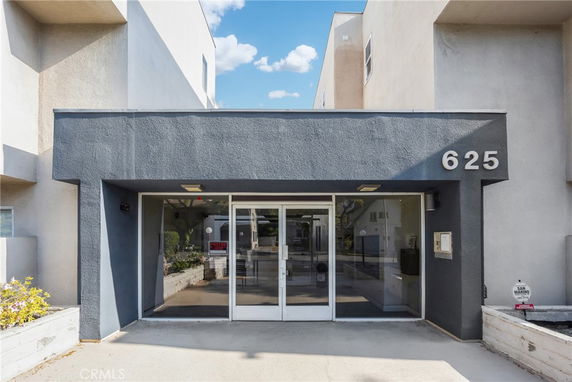 Front view of a modern building entrance with glass doors and number 625 displayed.