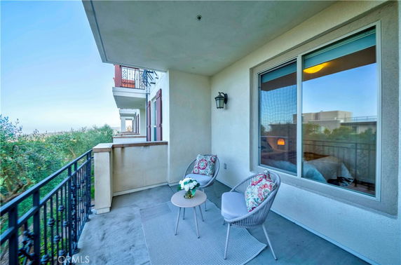 Outdoor balcony with seating area and partial view of surrounding areas.