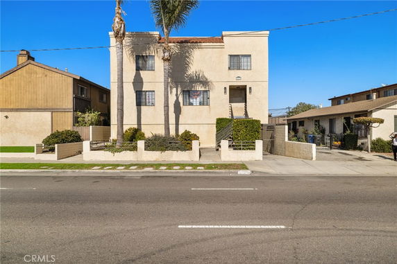 Front view of a two-story building with palm trees in front.