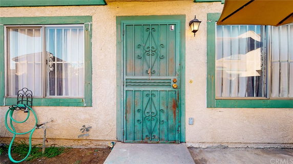 Front view of a house with a green door and two windows with bars.