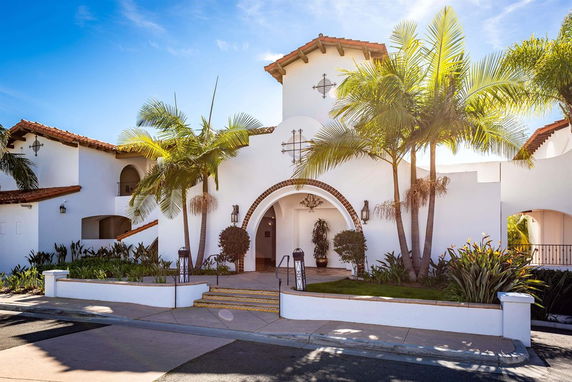 Front view of a house with arched entrance and white exterior walls.